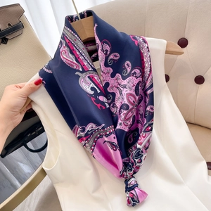 Detail of elegant paisley silk scarf in navy and pink draped on a wooden hanger