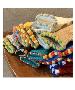 Dettaglio di guanti in maglia con pompon colorati e una calda trama spessa