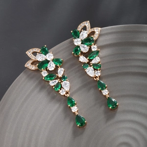 Detail view of emerald green teardrop drop earrings with gold finish and white crystals