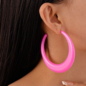 Close-up of a vibrant pink acrylic oversized hoop earring worn by a model