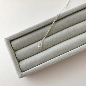 Minimalist 925 sterling silver necklace with faceted cube pendant on grey velvet box
