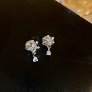 Macro shot of sparkling zircon snowflake earrings with teardrop crystal pendants