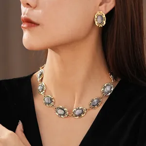 Vintage gold baroque jewelry set with oval gray resin stones on an elegant female model