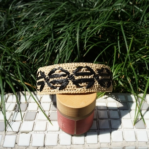 Close-up of beige raffia headband with black floral woven pattern for summer resort