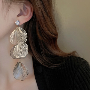 Detailed view of layered gold fan-shaped leaf drop earrings with sparkling rhinestones