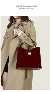 Detail view of burgundy suede handbag with brown leather trim and golden metal lock