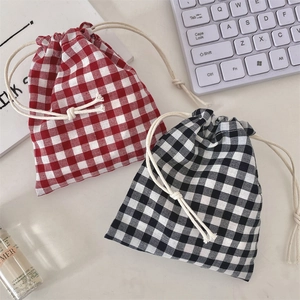 Detail of red and black checkered drawstring pouches on a minimalist desk setup
