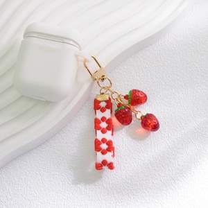 Close-up of strawberry keychain with embroidered floral ribbon and resin charms