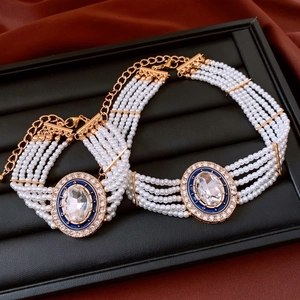 Detail of multi-layer pearl necklace with blue enamel and white zircon pendant in gold
