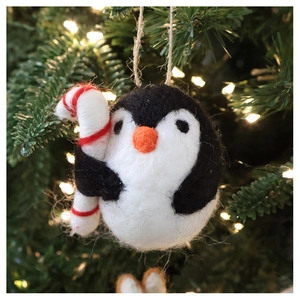Detailed view of handmade felt penguin Christmas ornament with striped candy cane and twine loop