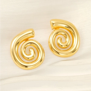Vista macro di orecchini a spirale in acciaio inossidabile placcati oro 18K su seta