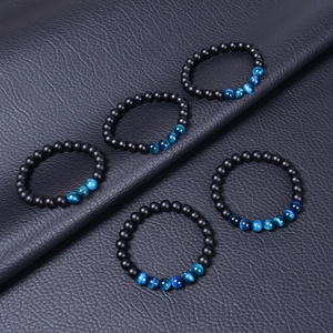 Détail de cinq bracelets en perles noires mates et œil de tigre sur cuir noir