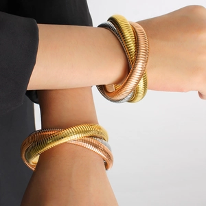 Close-up of three-layer coiled snake bone bracelets in gold, silver, and rose gold finish