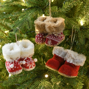 Red plush and knitted Christmas boot ornaments hanging on a lighted holiday tree