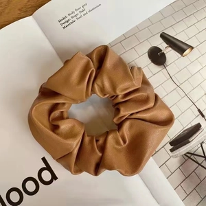 Detail of warm brown leather scrunchie with lychee texture on a vintage magazine