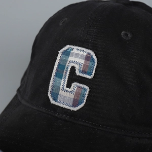 Macro detail of plaid letter C embroidery on black cotton baseball cap with stitch detail