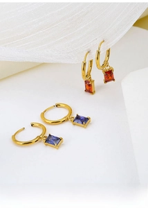 Detailed close-up of gold titanium steel earrings with red and purple zircon stones