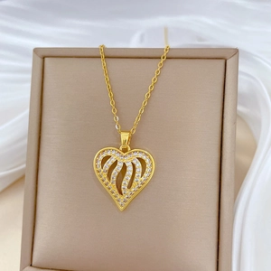 Elegant gold hollow heart pendant necklace with shimmering crystals on white silk