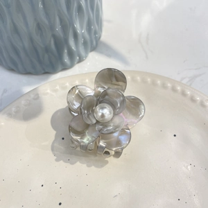 Detail of floral acetate hair claw with marble texture, pearl center, and iridescent shine