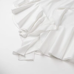 Détail du tissu en satin blanc doux avec bords à volants élégants et texture lisse