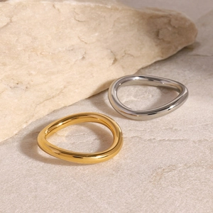 Macro shot of minimalist wave rings in gold and silver finish on organic stone