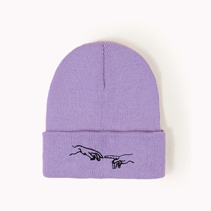 Détail du bonnet en maille côtelée lilas avec broderie noire de deux mains d'art
