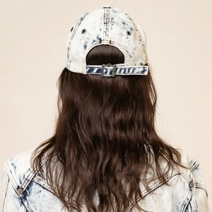 Close-up of acid wash denim baseball cap with embossed gothic cross metal buckle detail