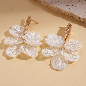 Detailed close-up of white textured petal tassel earrings with golden metal accents