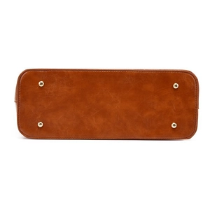 Detailed view of brown leather bag base with four protective gold metal feet for stability