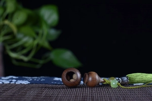 Detail of wooden aromatic sachet pendant with green jade-like beads and tassels