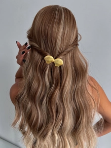 Gros plan détaillé d'une pince à cheveux dorée en forme de coquillage sur modèle