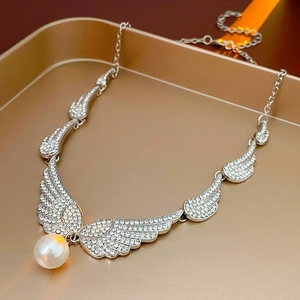 Macro detail of silver wing earrings with rhinestones and a dangling white pearl