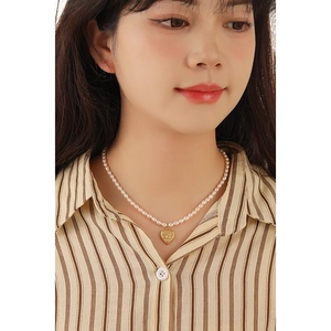 Elegant natural freshwater pearl necklace with a gold heart pendant on female model