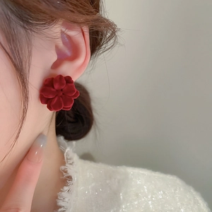 Close-up of a model wearing red flocked flower earrings with vintage velvet texture