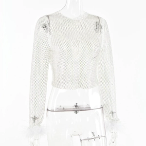 Détail d'un haut court en maille blanche avec strass et bordure en plumes aux poignets