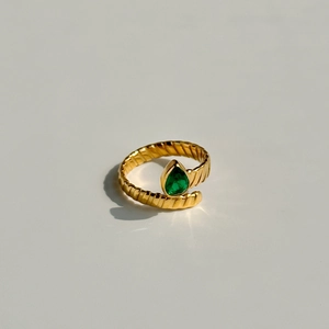 Macro detail of 18K gold-plated twisted ring featuring a pear-cut green zircon stone