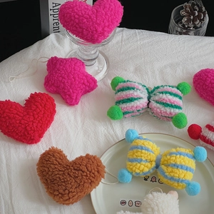 Detailed view of colorful lamb wool plush charms in heart, star, and bow shapes on a table