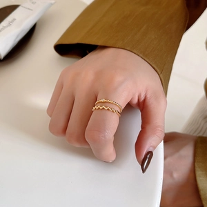 Detail of minimalist gold-plated ring set worn on hand with round beads and small zircon stone