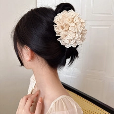 Detailed close-up of a large beige lace flower hair tie worn on a low bun hairstyle