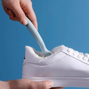 Long handle shoe brush in macaron blue color used for cleaning white casual sneakers