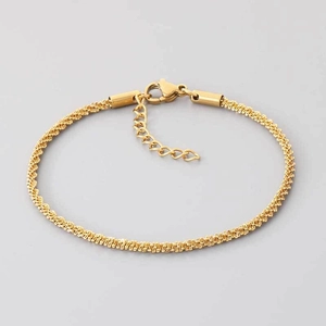 Gros plan d'un bracelet en chaîne torsadée dorée avec fermoir mousqueton et extension réglable