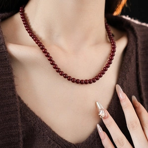 Detail view of a model wearing a deep red beaded titanium steel necklace with a glossy finish