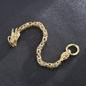 Gros plan d'un bracelet en métal doré à tête de dragon avec finition vintage polie sur gris