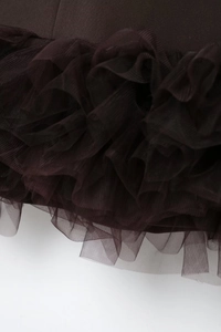 Macro detail of dark brown layered mesh fabric and ruffled hemline on the dress