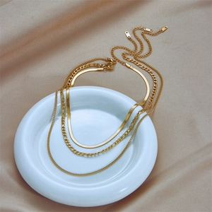 Three-layer gold titanium steel necklace with snake and Figaro chains on silk background