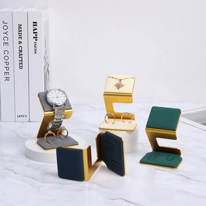 Luxury gold metal jewelry display trays with colorful velvet pads on marble surface