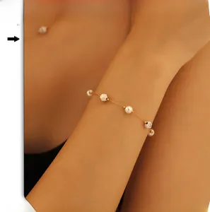 Détail du bracelet chaîne en or avec perles et pierres blanches sur le poignet du mannequin