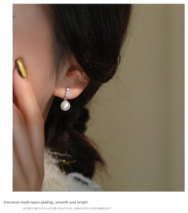 Macro shot of a French pearl earring with three bright zircon stones on a model ear
