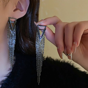 Detailed view of silver triangle tassel earrings with sparkling crystals worn by model
