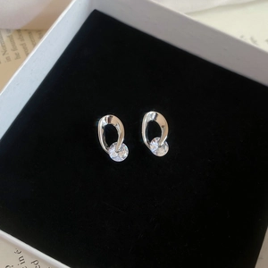 Macro shot of silver hollow oval studs with round cubic zirconia on a black velvet box